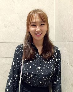 a woman standing in front of a white wall with stars on it's shirt