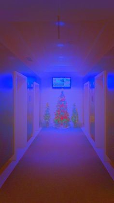 an empty hallway with christmas trees and televisions on the wall behind it in red and blue