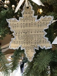 an ornament hanging from a christmas tree decorated with sheet music and snowflakes