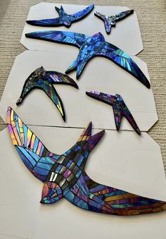 several pieces of stained glass sitting on top of a white board with birds painted on it