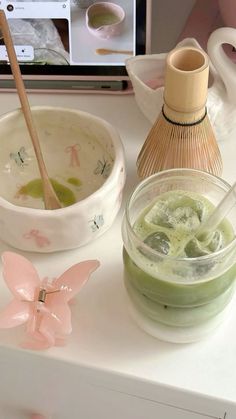 a table topped with bowls filled with green liquid and two wooden spoons next to each other