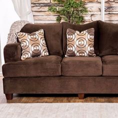 a brown couch sitting in front of a window with decorative pillows on top of it