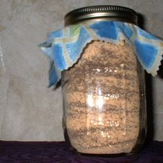 a jar filled with brown sugar sitting on top of a purple tablecloth covered table