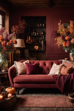 Enter Fall’s embrace with this cozy corner alcove, adorned with Fall wall decor that echoes a woodland in Autumn. The deep red walls and wooden bookshelf provide a splendid backdrop for enchanting Autumn wall art. The plush red sofa with earth-toned cushions, and a throw, invites hours of leisure. The natural elements, from autumnal blooms to pumpkins, complete the look, crafting an intimate space that is both a visual feast and a retreat for the soul. Salons Cottage, Fall Interior Design, Moody Living Room, Cozy Environment, Table Fireplace, Autumn Interior, Fall Lovers, Red Living, Fall Living Room