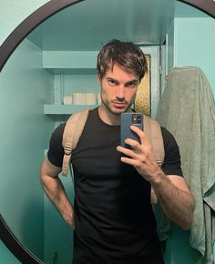 a man taking a selfie in front of a mirror with his cell phone and backpack