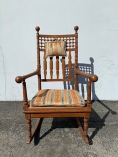 a wooden rocking chair with a striped cushion on it's seat and armrests