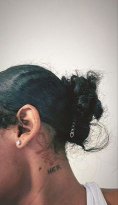 a woman with a tattoo on her neck and behind her ear is looking at the camera