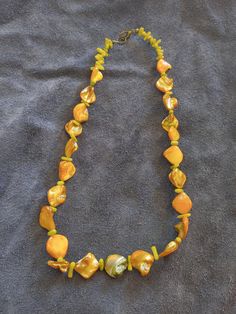 This necklace features golden colored Abalone shell beads and seafoam color dyed coral beads. This is a great addition to anyone who enjoys the beach life. Adjustable Gold Beaded Shell Necklace, Handmade Yellow Pearl Necklace For Gift, Yellow Single Strand Bohemian Necklace, Yellow Beaded Pearl Necklace Gift, Yellow Beaded Pearl Necklace As Gift, Yellow Bohemian Jewelry For Vacation, Yellow Bohemian Single Strand Necklace, Elegant Green Beach Jewelry, Elegant Green Jewelry For Beach