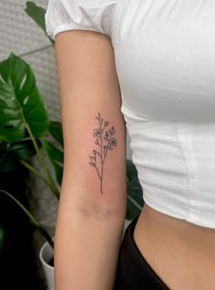 a woman's arm with a small flower tattoo on the left side of her body