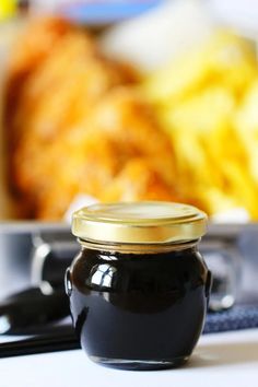 a black jar sitting on top of a table next to a plate with food in it