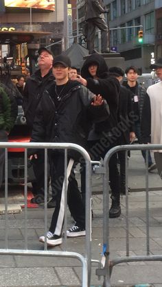 a group of people walking down a street next to a metal barricade