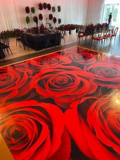 a room with red roses painted on the floor and tables set up for an event