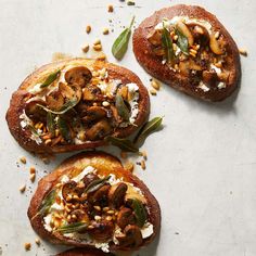 three pieces of bread topped with mushrooms and feta on top of a white surface