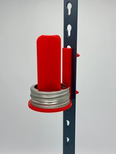 a red candle is sitting on top of a metal holder with two silver rings around it