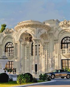 a car is parked in front of a large white building with ornate arches and columns