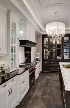 a large kitchen with white cabinets and black counter tops, along with a chandelier hanging from the ceiling