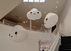 some white clouds hanging from the ceiling in a building with stairs and people walking up to them