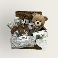 a teddy bear sitting on top of a basket filled with baby items