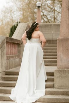 a woman in a white dress standing on some steps