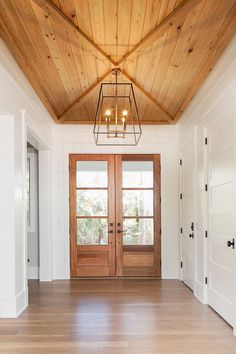 the inside of a house with two doors and a chandelier hanging from the ceiling