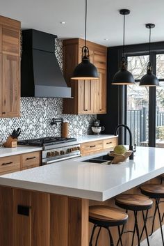 a large kitchen with wooden cabinets and white counter tops, black pendant lights over the island