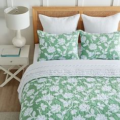 a bed with green and white bedspread in a bedroom next to a night stand