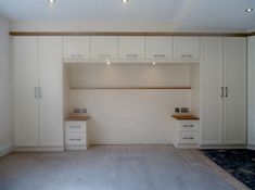 an empty room with white cabinets and drawers