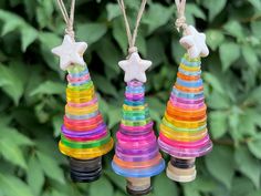 three colorful plastic christmas trees hanging from twine with star decorations on each ornament