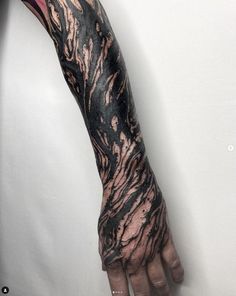 a man's arm covered in black and pink ink with his hand on it