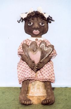 a black doll holding two hearts in her hands