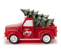 a red toy truck with christmas trees in the back and lettering joy on the side