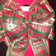 a red and green bow on top of a pink card board with gold foiling