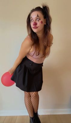 a woman with clown makeup holding a red frisbee in her right hand and wearing fish net stockings