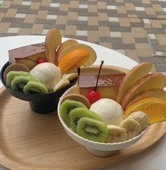 two bowls filled with fruit on top of a wooden platter next to each other