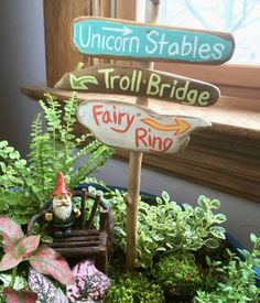 a sign that says fairy ring, unicorn stables and troll bridge in front of some plants