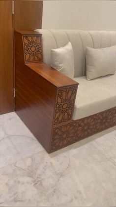 a white couch sitting on top of a marble floor next to a wooden cabinet and door