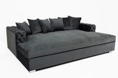 a large gray couch with lots of pillows on it's back and arms, sitting in front of a white background