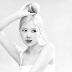 black and white photograph of a woman holding an apple on her head with both hands