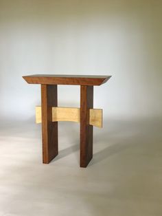 a small wooden table sitting on top of a white floor next to a gray wall