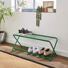 two pairs of shoes are sitting on a green metal shelf next to a potted plant