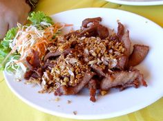 a white plate topped with bacon, lettuce and coleslaw next to a sandwich