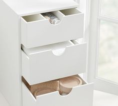 two drawers are open on the side of a white cabinet