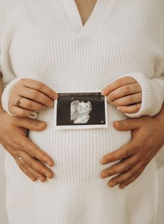 a pregnant woman is holding her stomach in front of the camera, with two hands on it