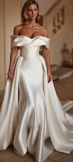 a woman in a white wedding dress standing on the floor with her hands on her hips