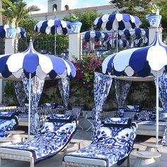 several blue and white umbrellas sitting next to each other on lounge chairs in front of a building