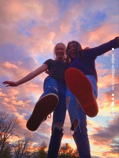 two girls are jumping up in the air with their skateboards at sunset or dawn