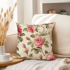 a coffee cup on a tray next to a flowered pillow in a living room