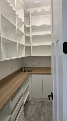 an empty kitchen with white cabinets and wood counter tops