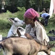 a woman sitting on the ground with two goats