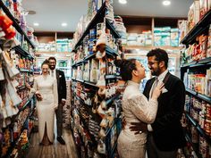 a man and woman standing in a grocery aisle surrounded by shelves full of food items